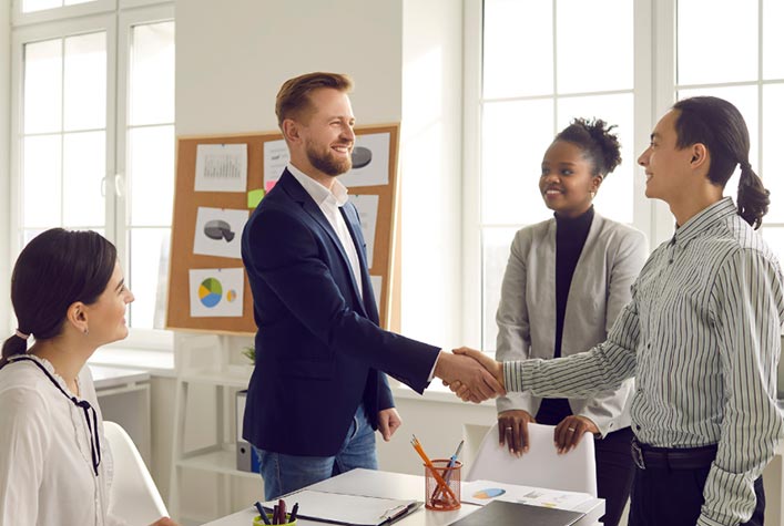 Happy and successful young professionals shaking hands